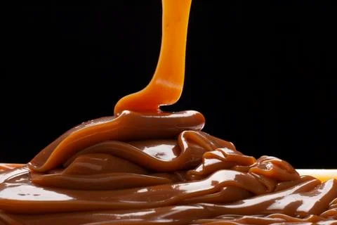 Dulce de leche spilled on a base with back light on black background. Foto stock