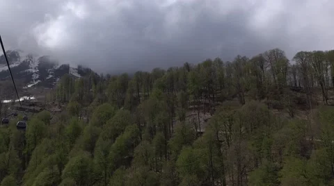Dull forested mountain edge, low cumulus clouds, aerial view from gondola lift 스톡 동영상 64239498