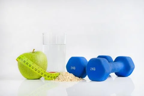 Dumbbell green apple and tape measure Stock Photos