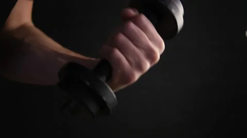 Dumbbell in hand close-up. A play of light and shadow. Black background. Exercis Stock Footage 147178491