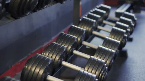 Dumbbell Rack: Close-up on a row of heavy metal dumbbells  Stock Footage 317784745