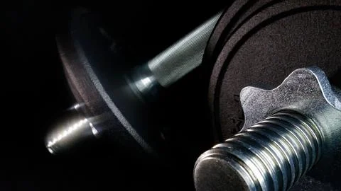 Dumbbell weights on dark background representing fitness power Stock Photos