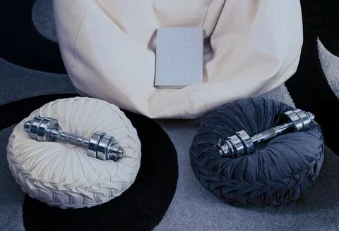 Dumbbells and book on cushions for relaxed home workout Stock Photos