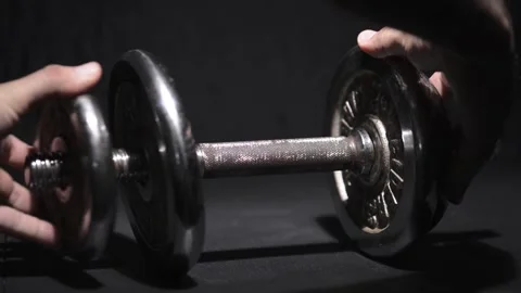 Dumbbells being loaded with plates and lifted on a dark blue background Stockbeeldmateriaal 150780225