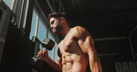 Dumbbells, exercise and bodybuilder man with music and serious for training Stock Photos