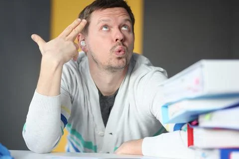 Dumbfounded man looks up next to folder with documents Stock Photos
