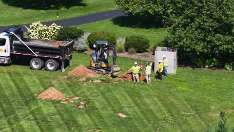 Dump truck and mini excavator move soil beside Trench Tech shoring box during Stock Footage 345322860