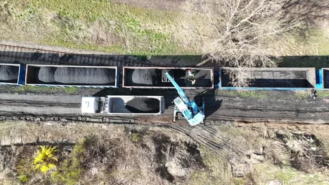 Dump truck being loaded with coal from freight train cars using crane Stock Footage 332132910