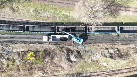 Dump truck being loaded with coal from freight train cars using a crane Stock Footage 334188294