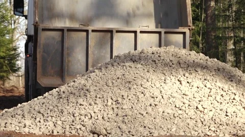 A dump truck is captured mid-action while unloading a large quantity of wet Stock Footage 323050026