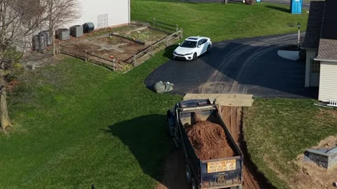 Dump truck delivering soil for backyard pool construction at suburban American Stock Footage 333923502
