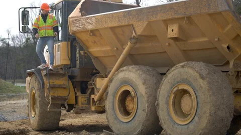 Dump truck driver climbs down the stairs of the cab at a construction site. Video stock 127123071