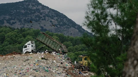 Dump truck opens up and out spills its load of rubbish over the garbage pile Stock Footage 274603652