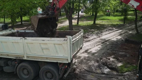Dump truck is parked while excavator shovel loads trailer with ground,crane shot Stock Footage 76656947