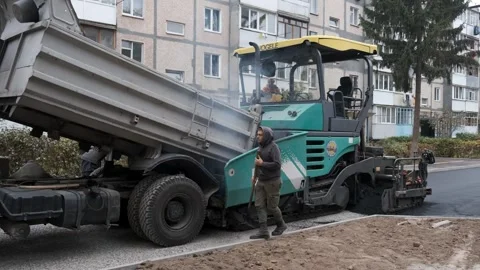 Dump truck unloading hot asphalt into paving machine on city street constru.. Vidéo 339802557