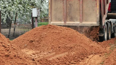 Dump truck unloading soil on a dirt road in a slavic village Stock Footage 312898251