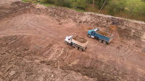 Dump trucks moving in reverse direction to unload the earth at the Stock Footage 125856570