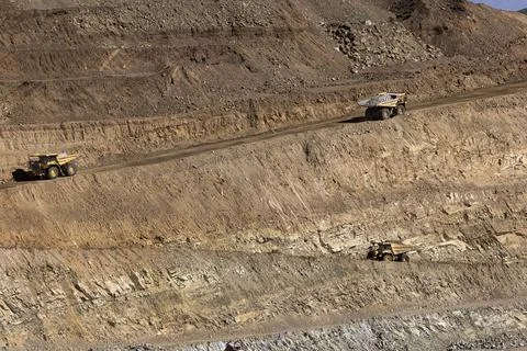 Dump trucks on steep zig-zag switchbacks in rocky pit mine 스톡 사진