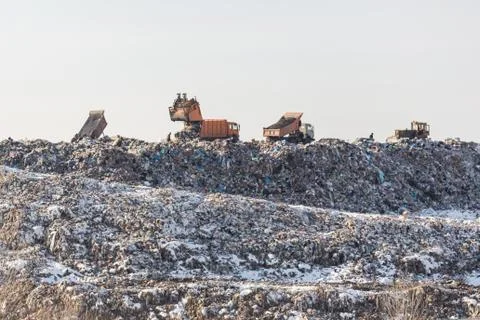 Dump trucks unloading garbage over vast landfill.  Environmental pollutio Stock Photos