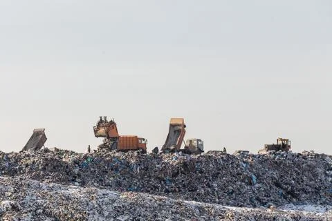 Dump trucks unloading garbage over vast landfill.  Environmental pollutio Stock Photos
