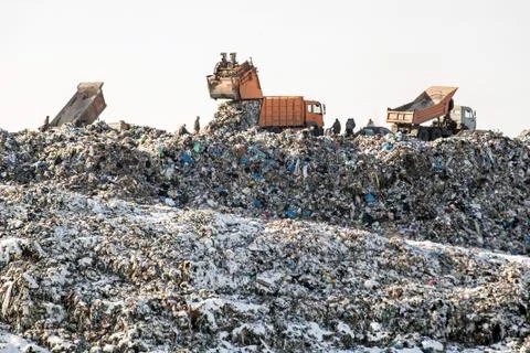Dump trucks unloading waste over huge sanitary fill.  Environmental pollutio Stockfoto's