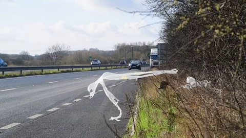 Dumped plastic rubbish in layby blowing in the wind united kingdom Stock Footage 124684868