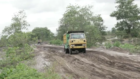 Dumper trucks of white sand mining pass over muddy road Stock Footage 160304060