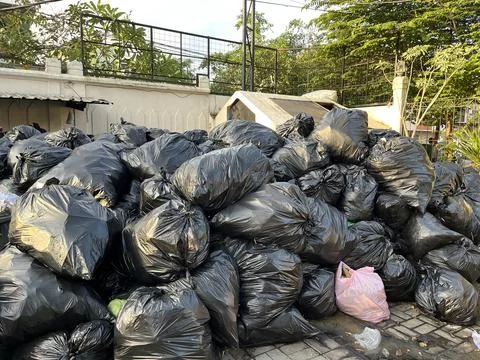 Dumping ground with pile of black garbage bags Stock Photos