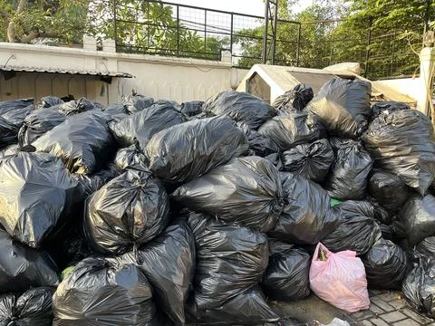 Dumping ground with pile of black garbage bags Stock Photos