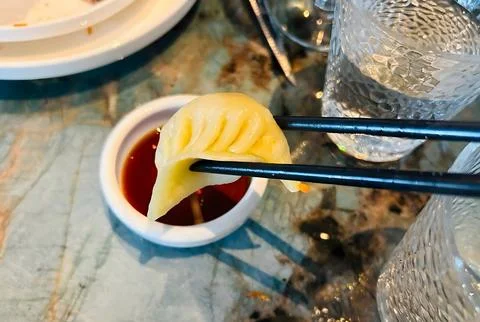 Dumpling dipping in soy sauce on a marble table. Stock-Fotos