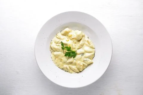 Dumpling from potatoes under cheese sauce. On a wooden background. Top view.  Stock Photos