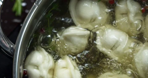 Dumplings are boiled in pot with boiling water with spices and spin on closeup Video stock 152093748