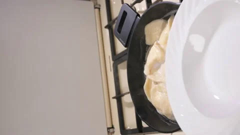 Dumplings are boiling. They are transferred to a white plate with a slotted Video stock 233155396