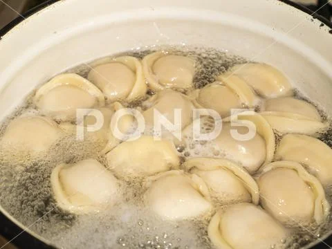 Dumplings from the dough with meat are boiled in boiling water. Stock Photos