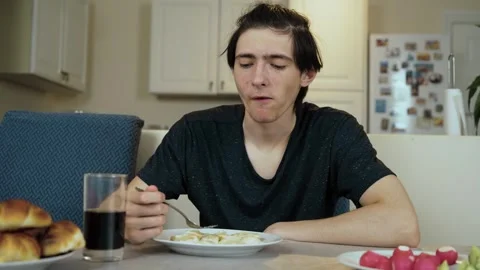 Dumplings on plate while young man sitting in kitchen with calm expression Stock Footage 328370761