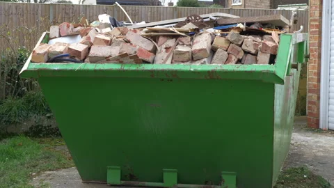 A dumpster or skip, full to overflowing with bricks and other building waste. Stock Footage 270176612