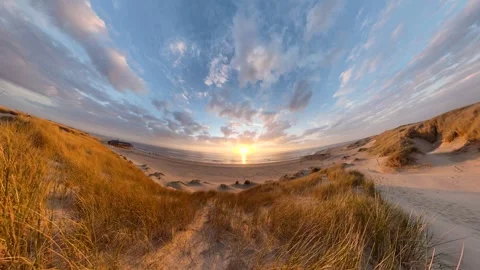 A dune covered in dune grass by the sea at sunset, Video-Effect 库存影片 334737175