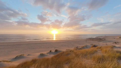 A dune covered in dune grass by the sea at sunset, pan 库存影片 334737180