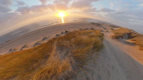 A dune covered in dune grass by the sea at sunset, Video-Effect Stockbeeldmateriaal 334737218