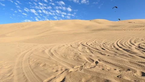 Dune slopes with tire tracks and paragliders soaring under a bright blue sky. Stock-Footage 345681931