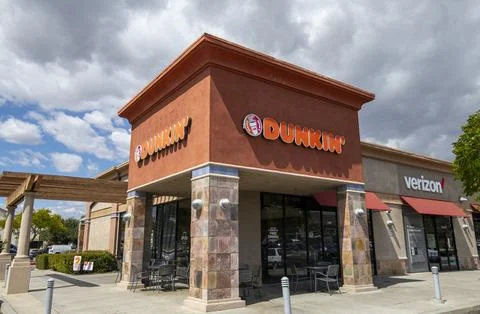 Dunkin Donuts store front, logo, sign, signage, marquees, entrance, clouds. Stock Photos