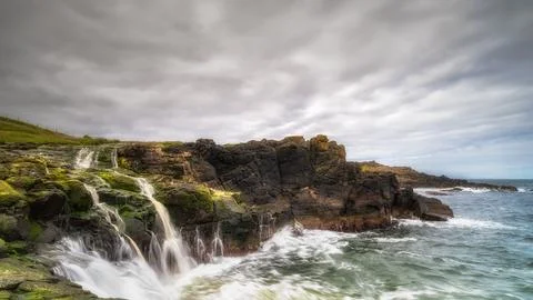 Dunseverick Falls with small cliffs and streaks of water falling down to At.. Foto stock