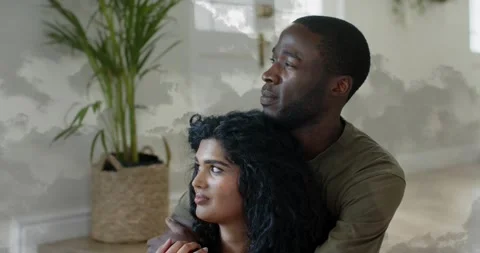 Duo embracing by plant, man adjusting and leading woman gazing out window Stock Footage 330646724