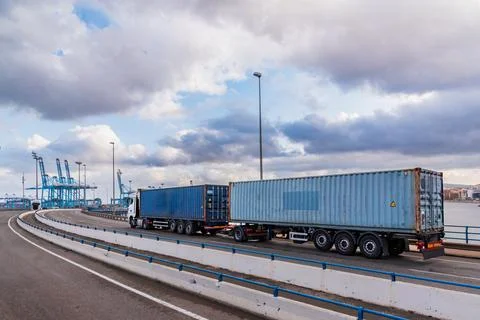 Duo trailer with containers circulating through the entrance bridge to the .. Stock Photos