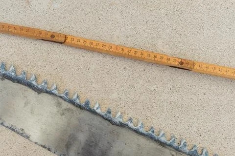 Durable old saw blade and a wooden folding ruler laying on a light textured.. Stock Photos