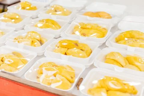 Durian fruit is shown in plastic containers at a market. The fruit is yellow  Stock Photos