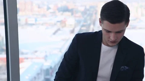 During a Break, sits on a background of a large window with a laptop Stock Footage 70864496