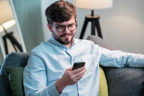 During a break in work at home, a bearded employee picked up the phone and dials Stock Photos