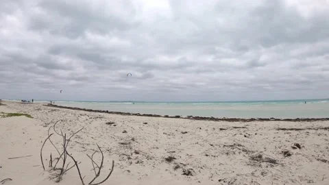 During a cloudy day there are people doing kiteboarding on a paradisiac Vídeo Stock 155097498