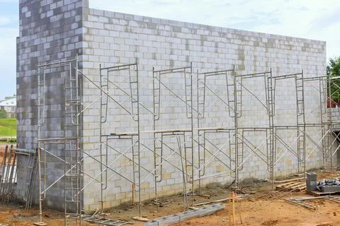 During construction, mason makes concrete wall from cement blocks while standing Foto stock